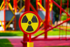 A radiation hazard sign is posted on a fence that separates a contaminated nuclear test site.