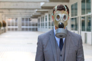 Picture of a man in a suit wearing a gas mask due to radiation exposure that can cause cancer.