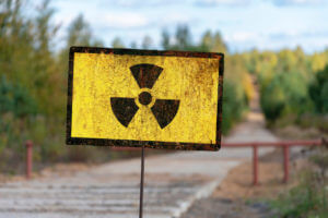 Old textural Sign of radiation hazard against the background of infected nature and forest.