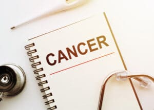 Medical Concept - Cancer words written on notebook with Stethoscope and thermometre on white background